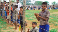 refugee children wait behind barbed wire Picture: CAFOD