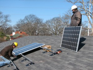 workers install solar panels on church roof