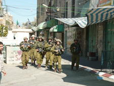soldiers marching past Hebron shops