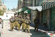 soldiers marching past Hebron shops