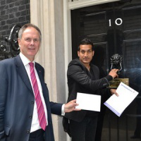 ACN national director Neville Kyrke-Smith & march organiser Wilson Chowdhry present petitions to Downing Street.
