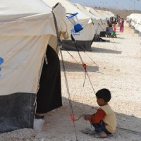 Young refugee  by family tent at displacement camp in Jordan