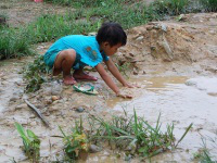 child looks for water by refugee camp in Burma