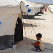 Young refugee by family tent