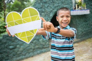 Martin from Myanmar, with CAFOD Climate Change Heart. Campaigners are saying what they love that is at risk due to climate change. Martin said 'the human race'  Pic: Ben White