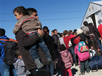 Man carries child at Macedonia-Greece border / JRS