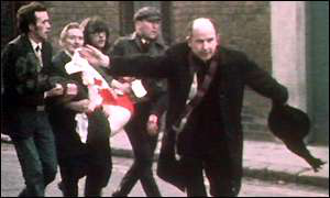 Fr Edward Daly, waving a blood-stained white handkerchief as he escorts a mortally-wounded protester to safety during Bloody Sunday. Wiki image