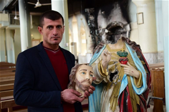 Christian holds statue beheaded by Daesh, St Addai Church, Keramlis, Iraq