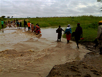 People cross river swollen by recent rain