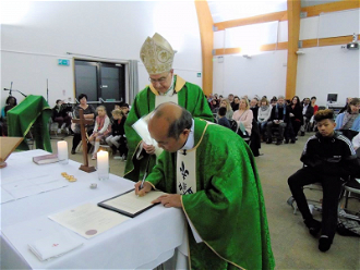Fr John signs the profession of faith in Cambourne.