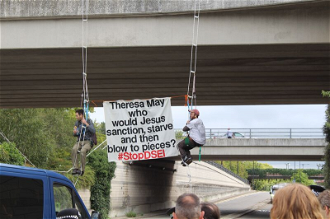 The banner reads: 'Theresa May - Who would Jesus sanction, starve and blow to pieces? #STOP DSEI