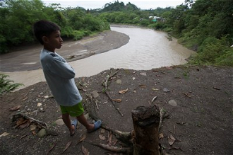 Boy observes effects of erosion caused by sand mining in Carepa river, Colombia. ©Sean Hawkey/WCC
