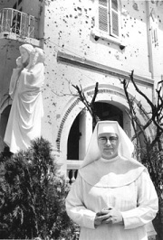Sr Mary in front of bullet-riddled orphanage