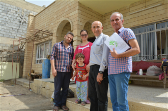 Qaraqosh - Fr George Jahola (2nd right) with family at repaired home ©Aid to the Church in Need.