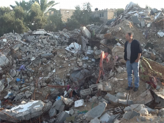 Saad Ziada standing on ruins of his home where 6 family members from 3 generations were killed