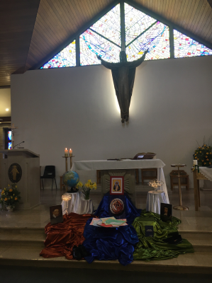 Icon of Rosalie Rendu before the altar, with red, blue and green cloths symbolising the Daughters of Charity worldwide reach
