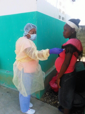 Casimir Merline, trained by Midwives for Haiti, screens a pregnant patient for COVID-19 at Montegrande Community Clinic, Haiti