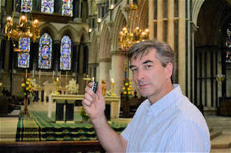 Darren Butler in St John's Cathedral, with the tiny remote control for its new live-streaming system.