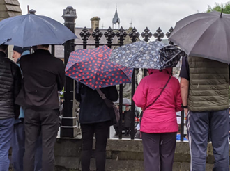 Mourners huddled in the rain - image: Mary  Carson