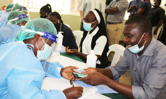 Pastoral team in PPE at vaccination centre © ACN