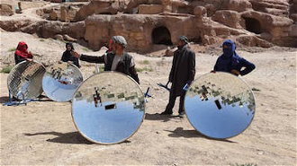 Afghan Villagers stand with solar pots donated by local solidarity youth group. Each pot can be used to boil a kettle or cook a family meal.