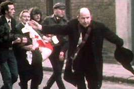 Fr Edward Daly waving blood-stained handkerchief as he escorts mortally-wounded boy to safety on Bloody Sunday.  image by BBC journalist John Bierman. Wiki Image