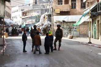 Heavily armed soldiers check primary school children on the way to school and the way home