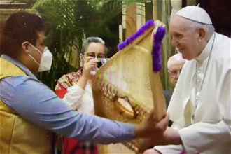A member of the Assembly of First Nations delegation presents Pope Francis with snowshoes made from ashwood by elders from the Cree community in Quebec