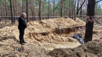 Cardinal Krajewski prays at mass grave in Izium. Image Vatican News