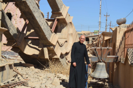 Fr George Jahola next to church's ruined bell tower in 2017 © ACN.