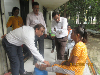 Dr VV Pai examines young patient with government officials.  Image: St Francis Leprosy Guild