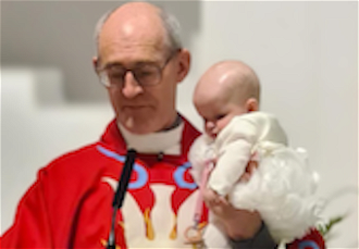 Fr Mark calms noisy baby as he reads parish announcements