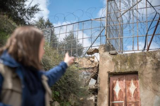 Nora from Finland points to a kindergarten, as EAPPI international participants undertake a 'school run' in  H2 area of Hebron, protecting Palestinian children fron attacks by settlers by their presence. Photo: Albin Hillert