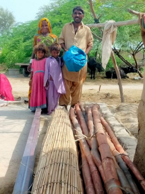 Family with roofing materials - ready to put on their new mudbrick house