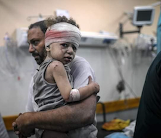 Father hugs son rescued from their destroyed house in Khan Yunis. Image N Khalid