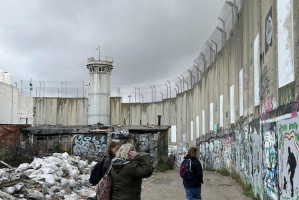 Pilgrims walk by Separation Wall, Bethlehem. ICN/JS