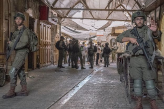 Soldiers lead illegal Israeli settlers through market