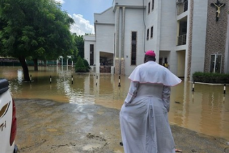 Bishop John Bakeni in front of  water-logged cathedral © ACN