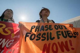 Woman holds banner  at COP28, Dubai, UAE.  Image Hillert-20231204_AH1_6748