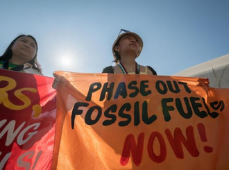 Woman holds banner  at COP28, Dubai, UAE.  Image Hillert-20231204_AH1_6748