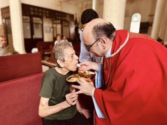 Fr Gabriel gives Communion to parishioner
