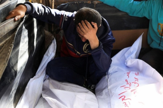 Desolate mourner besides the bodies of members of the Al-Arabeed family killed in Israeli strikes, at Al Shifa hospital, in Gaza City