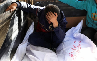 Desolate mourner besides the bodies of members of the Al-Arabeed family killed in Israeli strikes, at Al Shifa hospital, in Gaza City