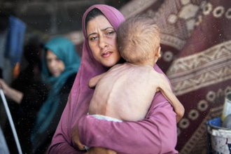 Mother holds two-year-old son, suffering from malnutrition, losing more than seven pounds in just a few months. Photo: Diaa Ostaz