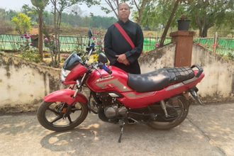 Father Arvind Tigga with one of the new bikes. Image: ACN