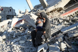 Mother and child on ruin of their home