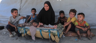 Displaced family in front of their tent in Gaza. © UNICEF/Mohammed Nateel