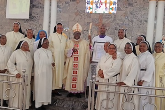 Tobias Yahaya hold his award next to Bishop Matthew Kukah during the special Mass