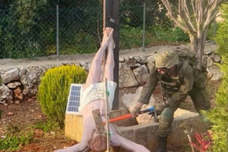 IDF soldier hitting crucifix with hammer (from social media by Younis Tirawi)
