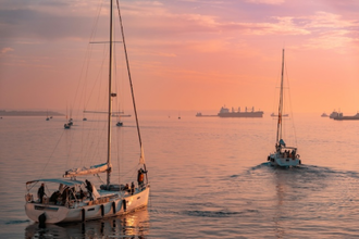 Sailboats in sunset coming into port of Thessaloniki - photo by Jim Makos on Unsplash